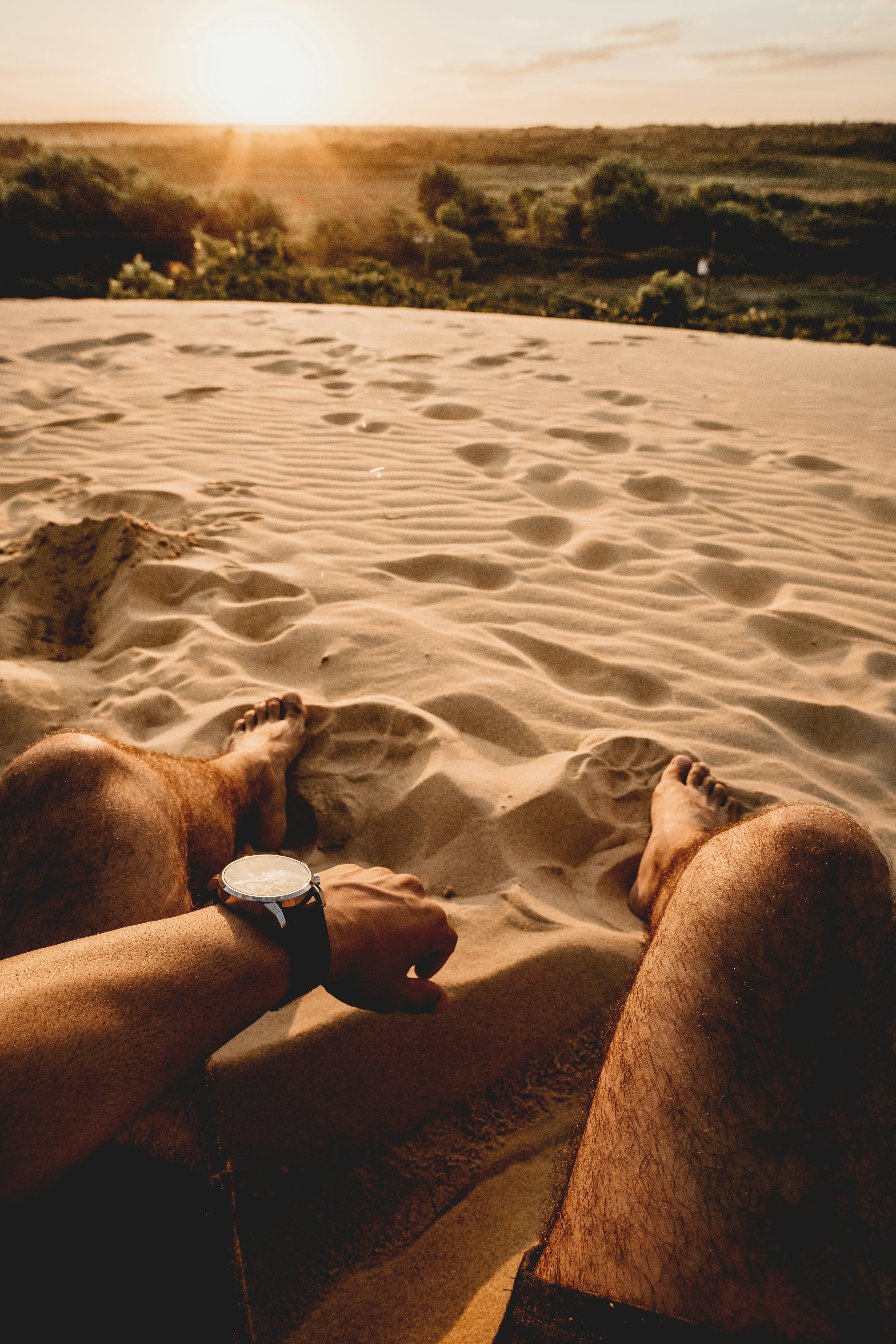 man sitting on sand during daytime